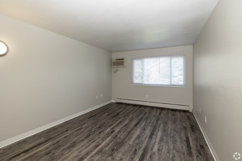 A room with a window and a wooden floor.