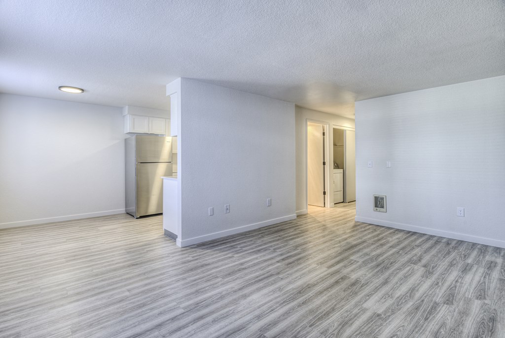 the living room and kitchen of an empty apartment with wood flooring
