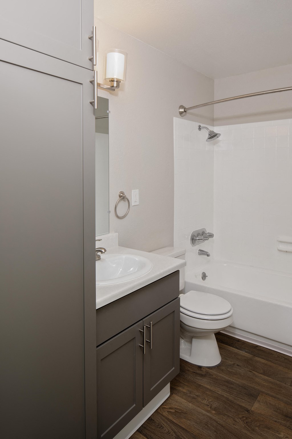 a bathroom with gray cabinets and a white bathtub