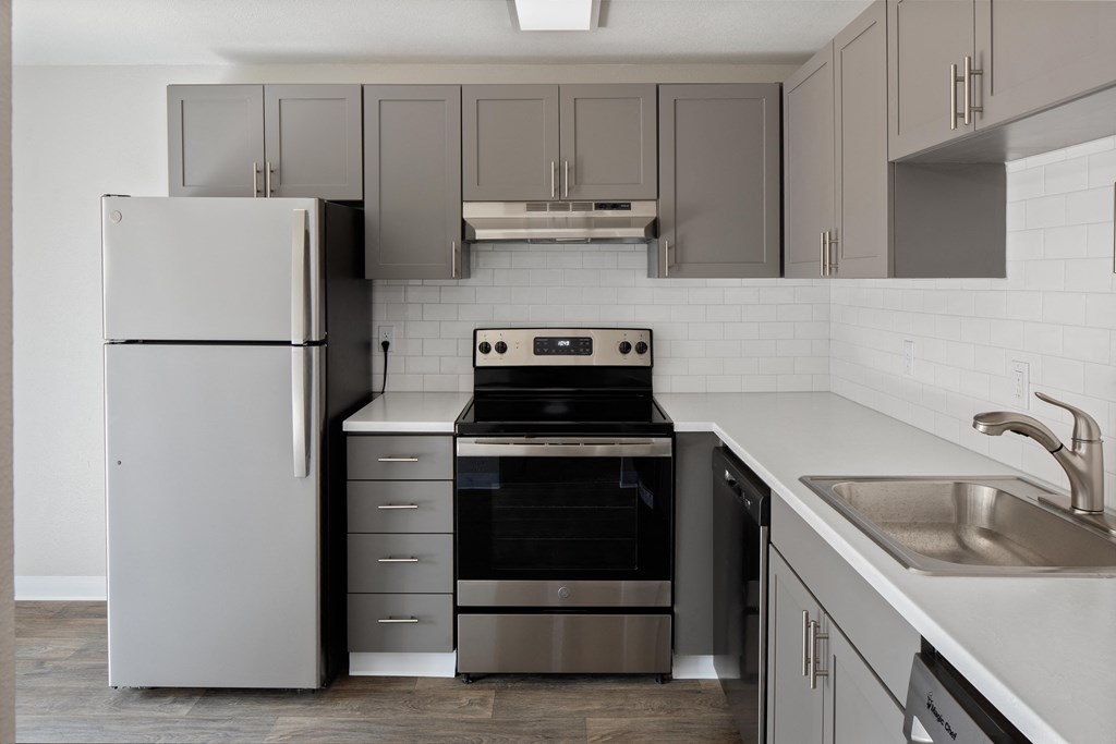 a kitchen with gray cabinets and stainless steel appliances