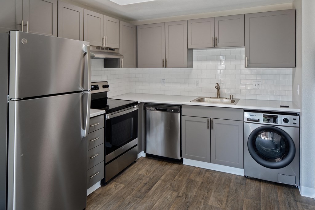 a kitchen with gray cabinets and stainless steel appliances