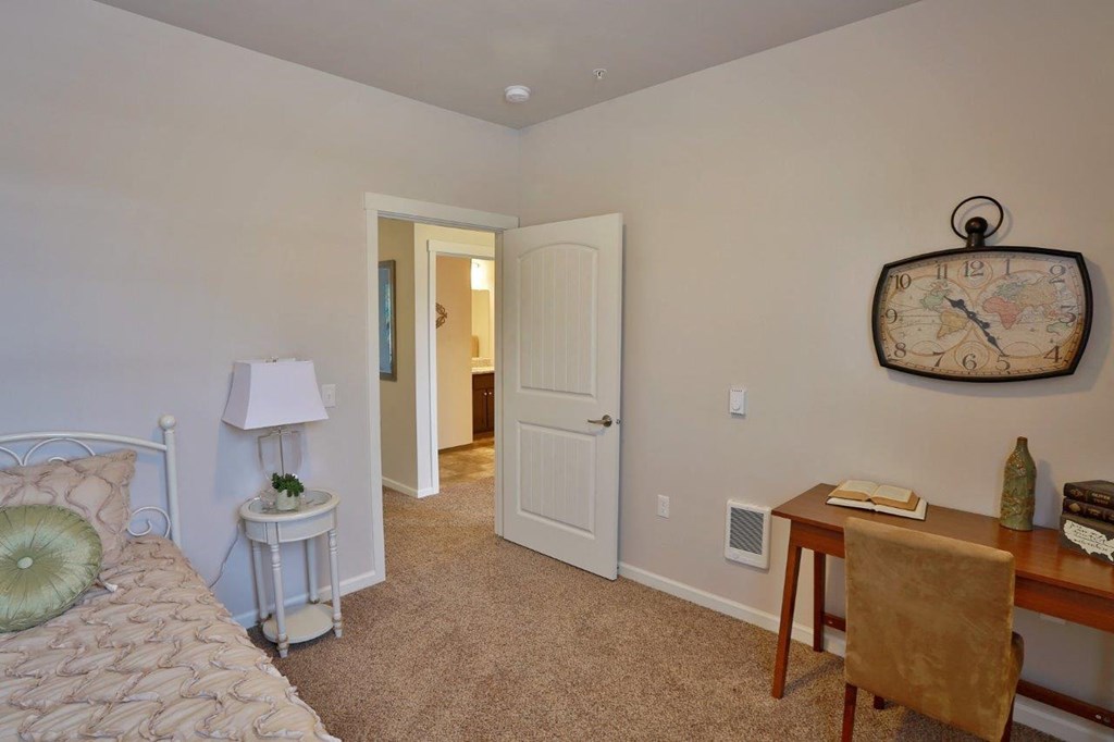 a bedroom with a bed and a desk with a clock