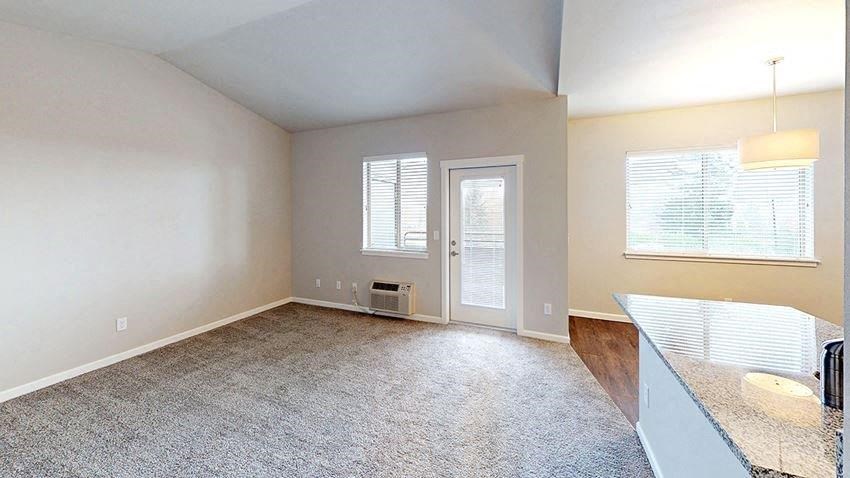 an empty living room with a kitchen and a door