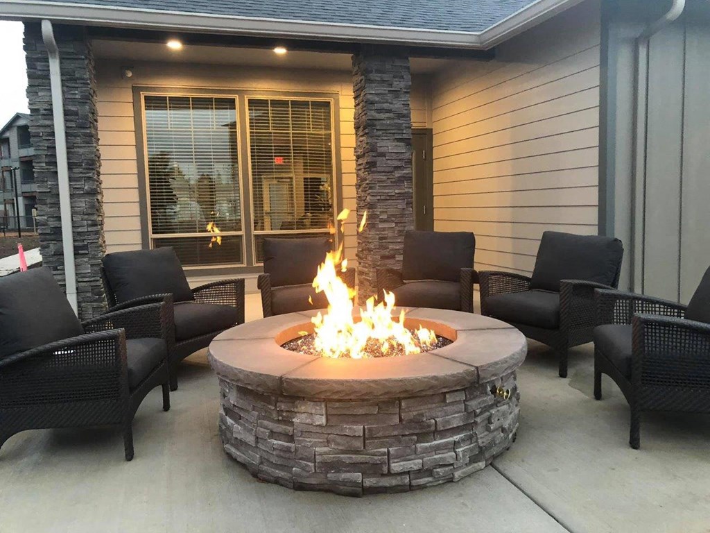 a fire pit on the patio of a home with chairs