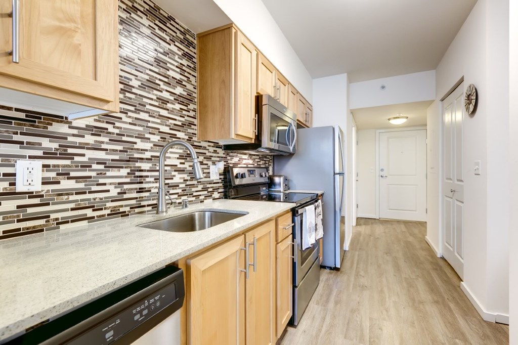 A kitchen with wooden cabinets and a black dishwasher.