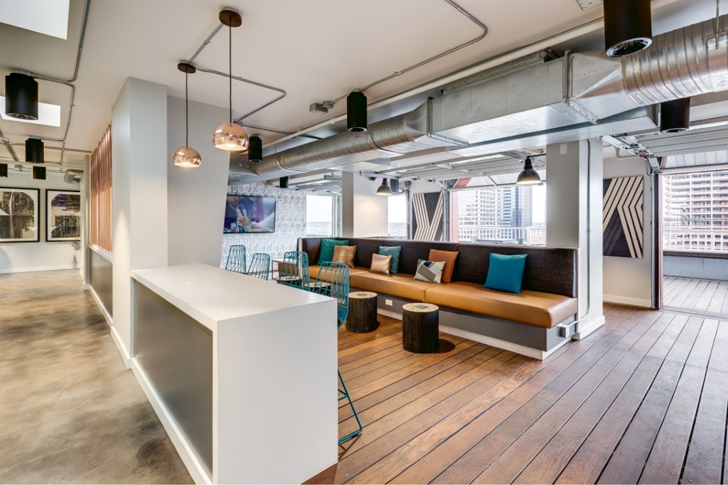 A modern interior with a white reception desk and a long wooden bench with blue cushions.