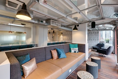 A modern living room with a brown couch and a glass table.