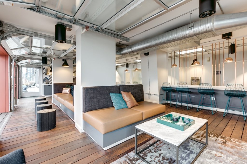 A modern living room with a long sofa, a coffee table, and a glass table with stools.