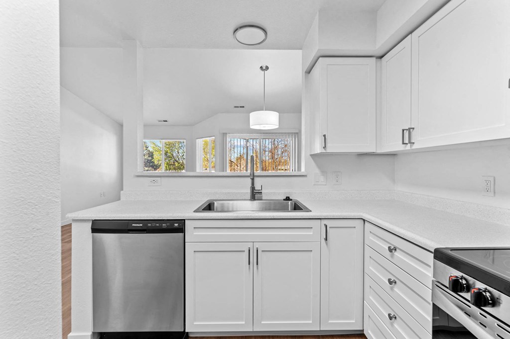 a white kitchen with white cabinets and a stainless steel sink