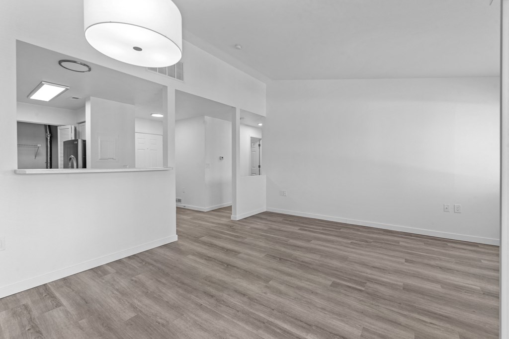 the living room and kitchen in a new home with white walls and wood flooring