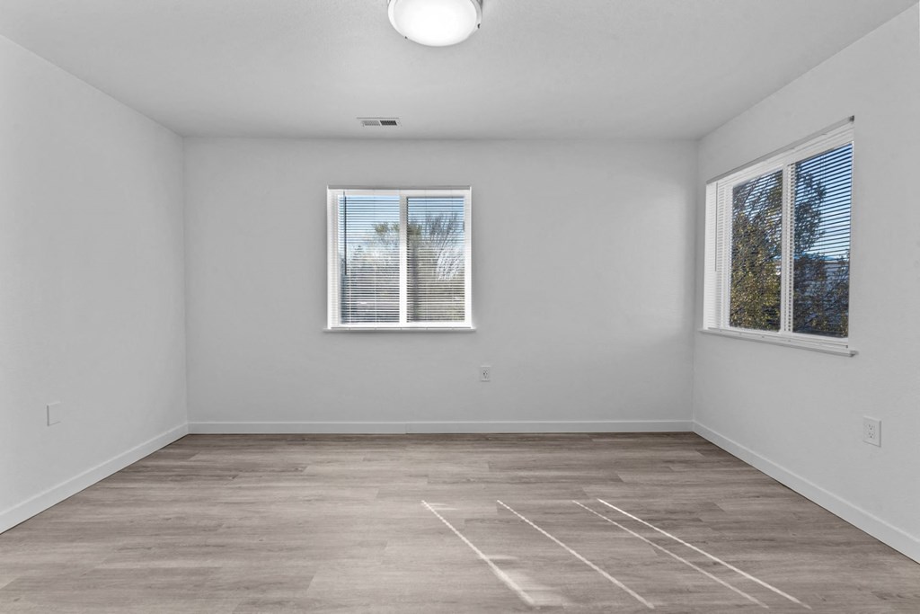 an empty room with two windows and white walls