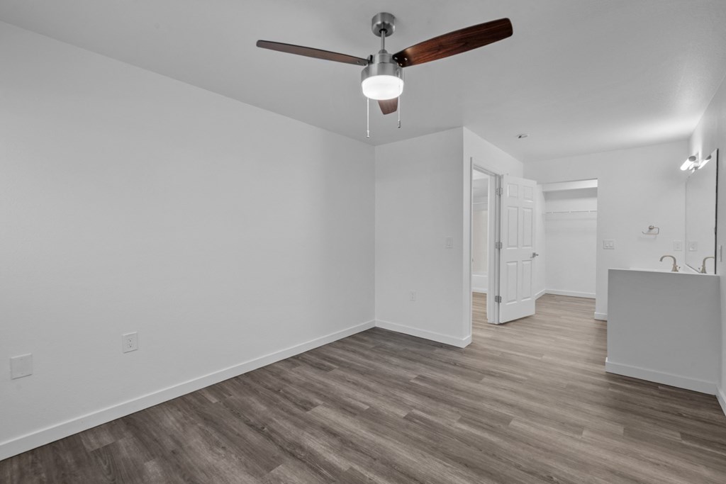 a living room with white walls and a ceiling fan