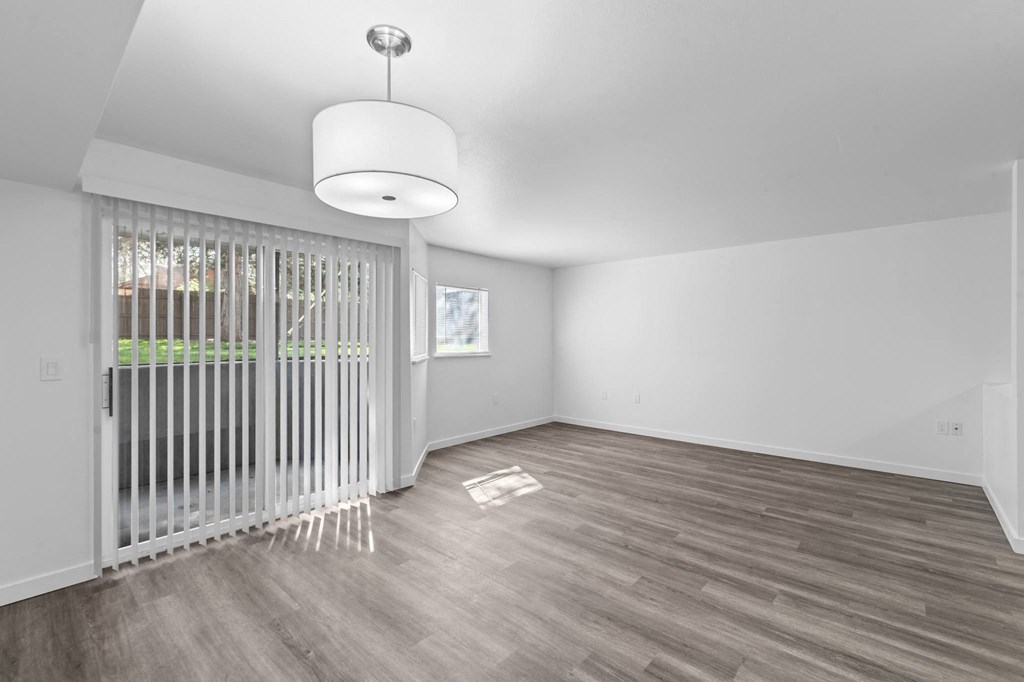 an empty living room with a sliding glass door and a lamp