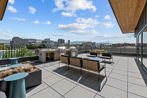a rooftop patio with a barbecue grill and a view of the city