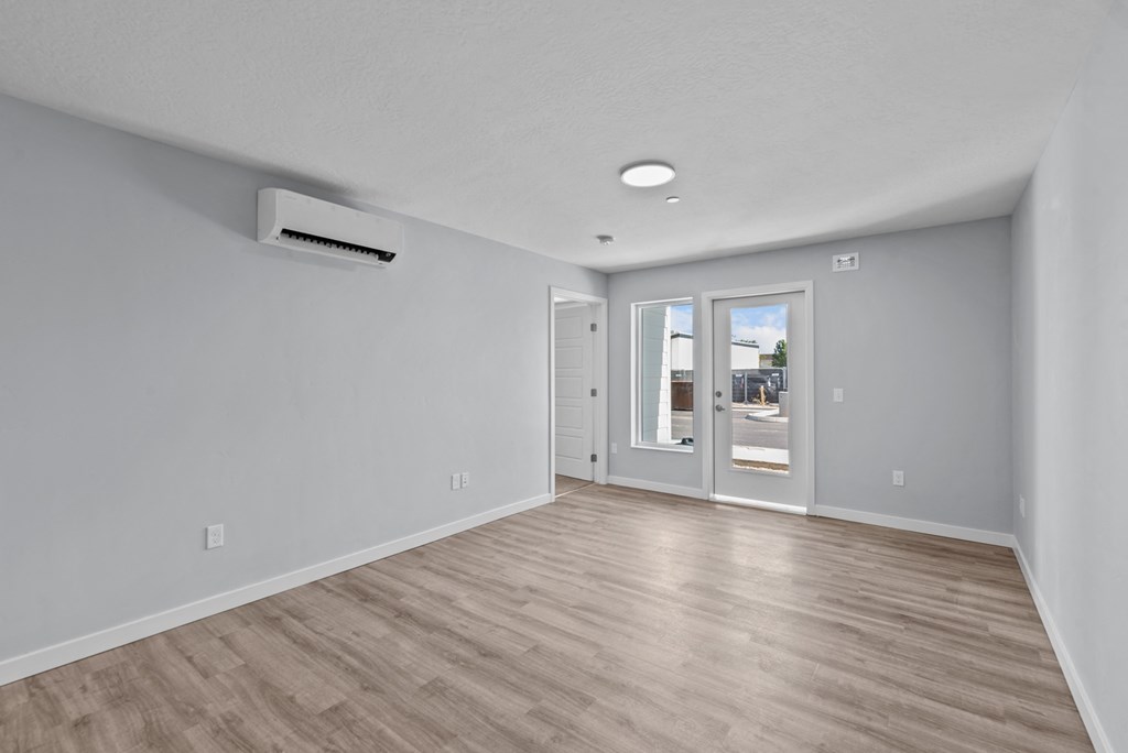 a spacious living room with hardwood floors and grey walls
