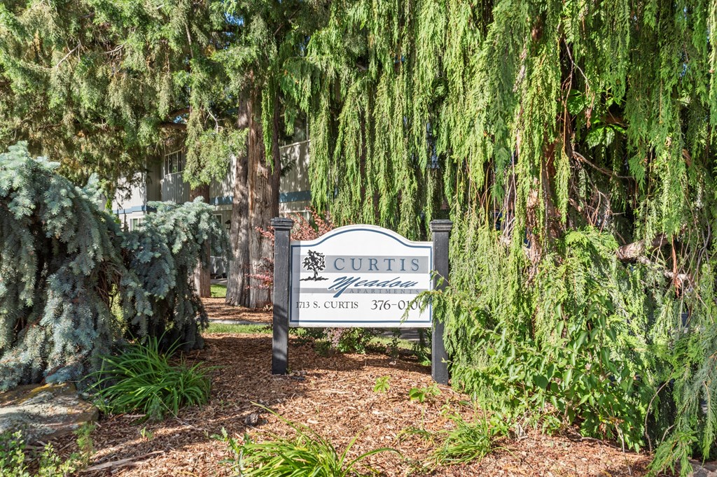 Curtis Apartments sign in front of some trees and plants