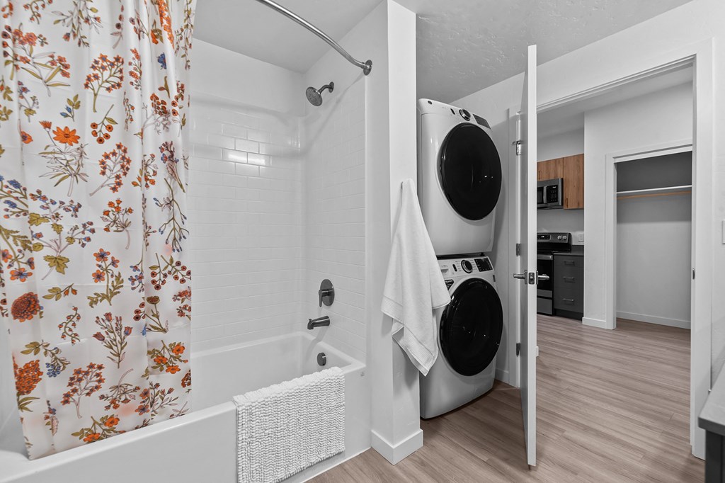 a laundry room with a washing machine and a tub and a shower curtain