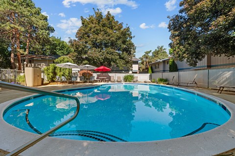 a swimming pool with trees in the background and a fence