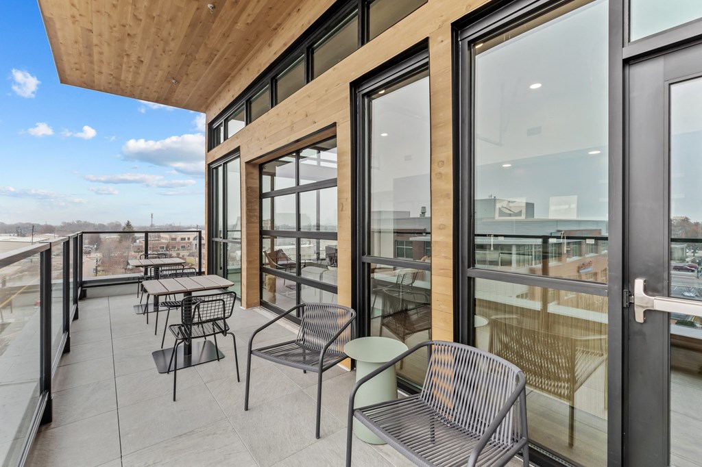 a balcony with tables and chairs and glass doors