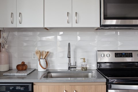 Grant Park Village kitchen sink shot with white tile backslash and electric stove