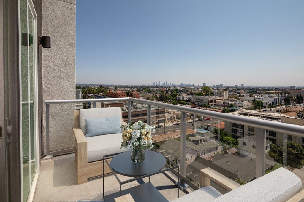 A balcony with a chair and a table with flowers on it.