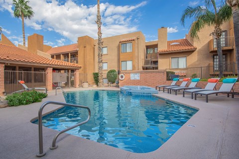 A pool surrounded by sun loungers and palm trees.