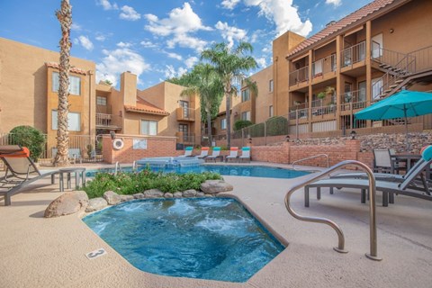 A pool surrounded by a patio with chairs and umbrellas.
