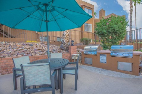 A patio with a table and chairs under an umbrella.