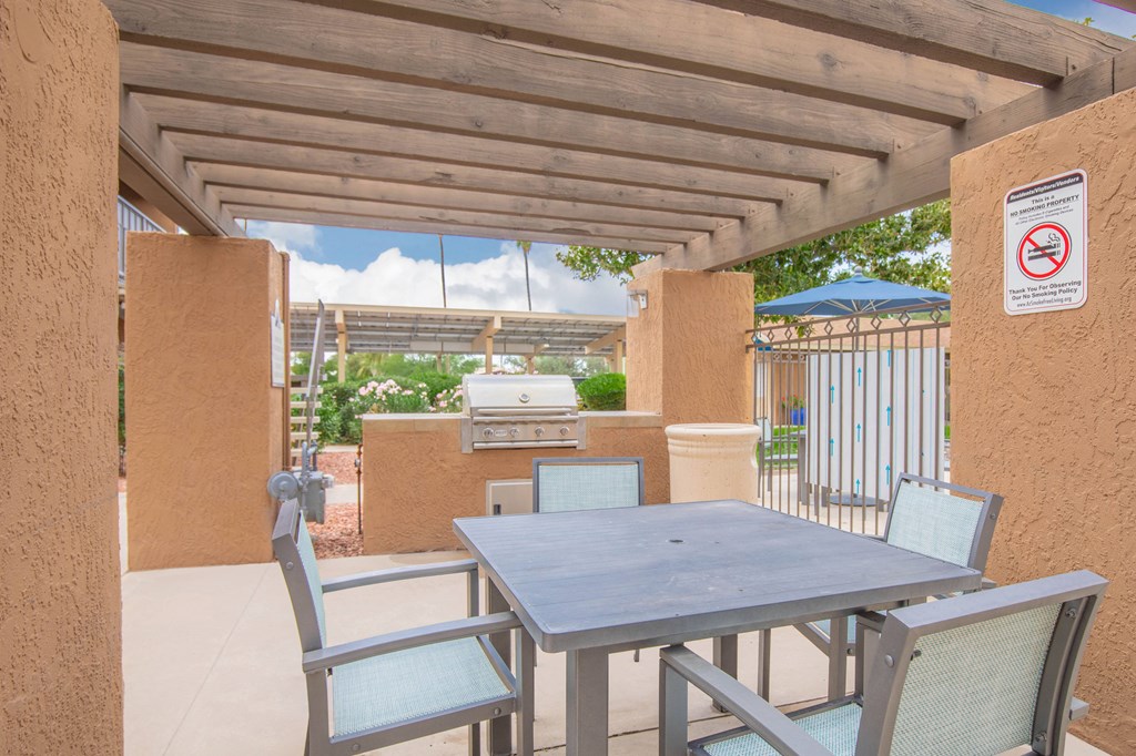 A patio with a table and chairs under a roof.