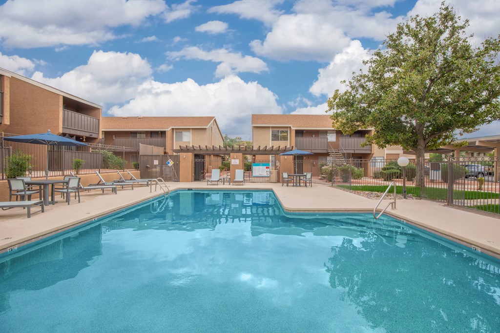 A large swimming pool in front of a building with a tree on the right side.