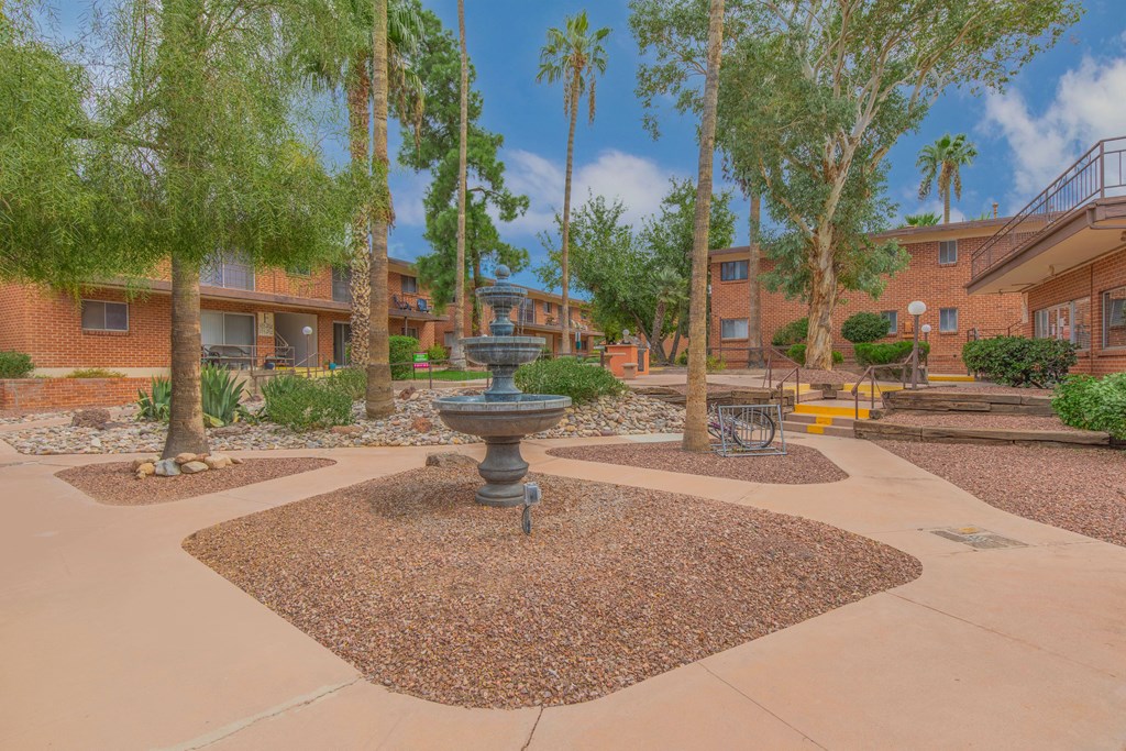 A courtyard with a fountain surrounded by trees and buildings.