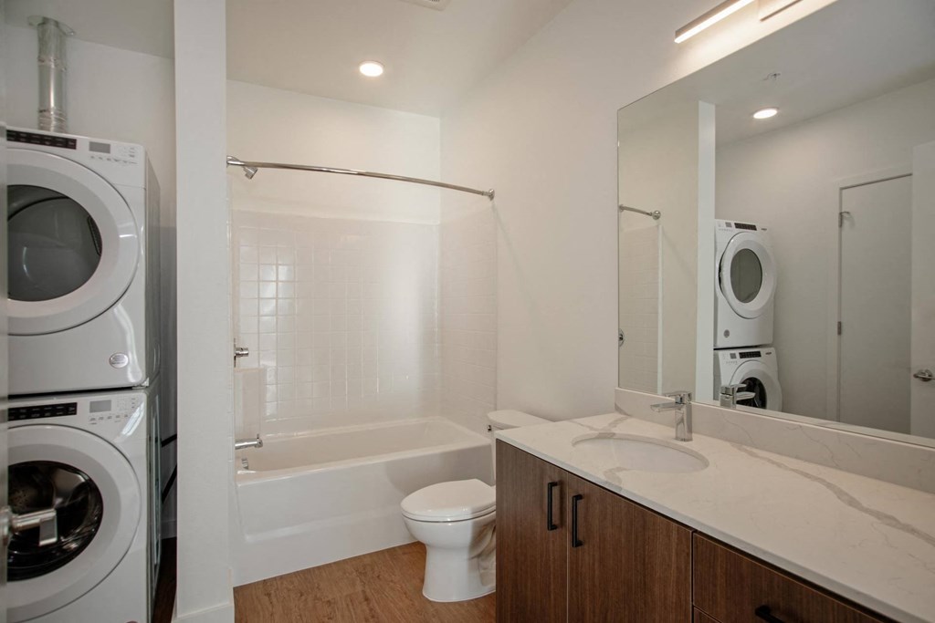a bathroom with a washer and dryer in it and a toilet and sink