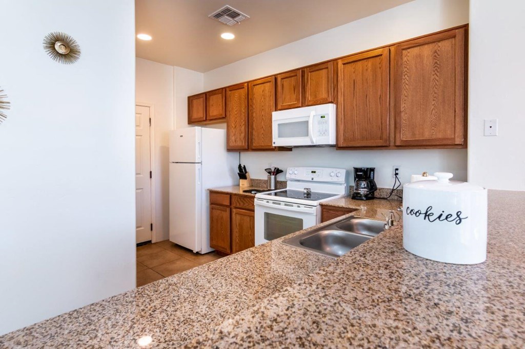 A kitchen with granite countertops and wooden cabinets.