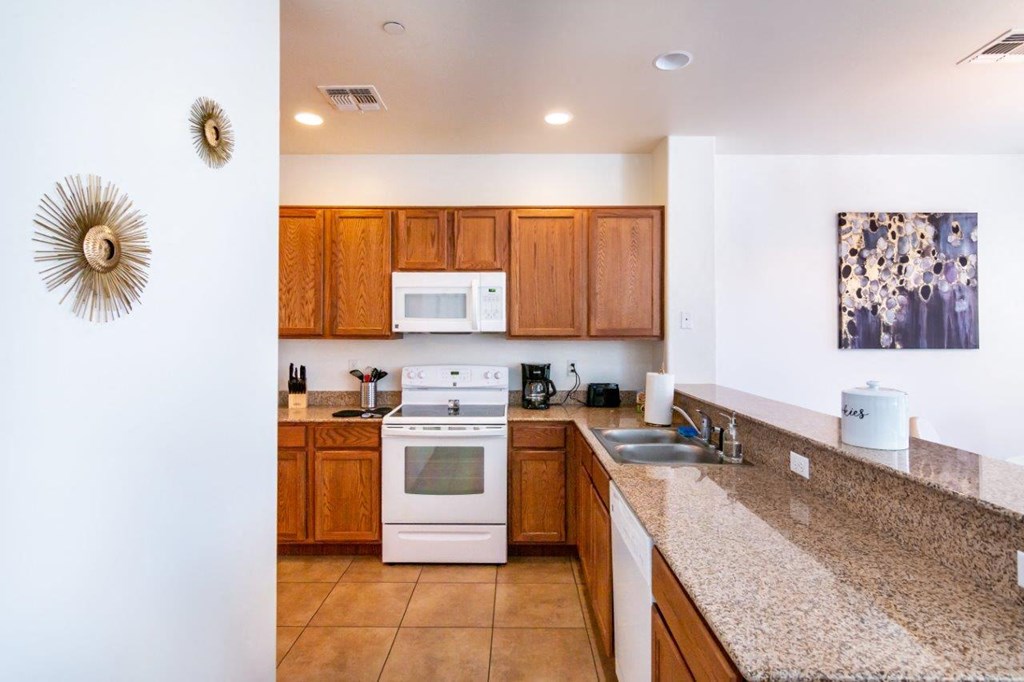 A kitchen with a white stove top oven and wooden cabinets.