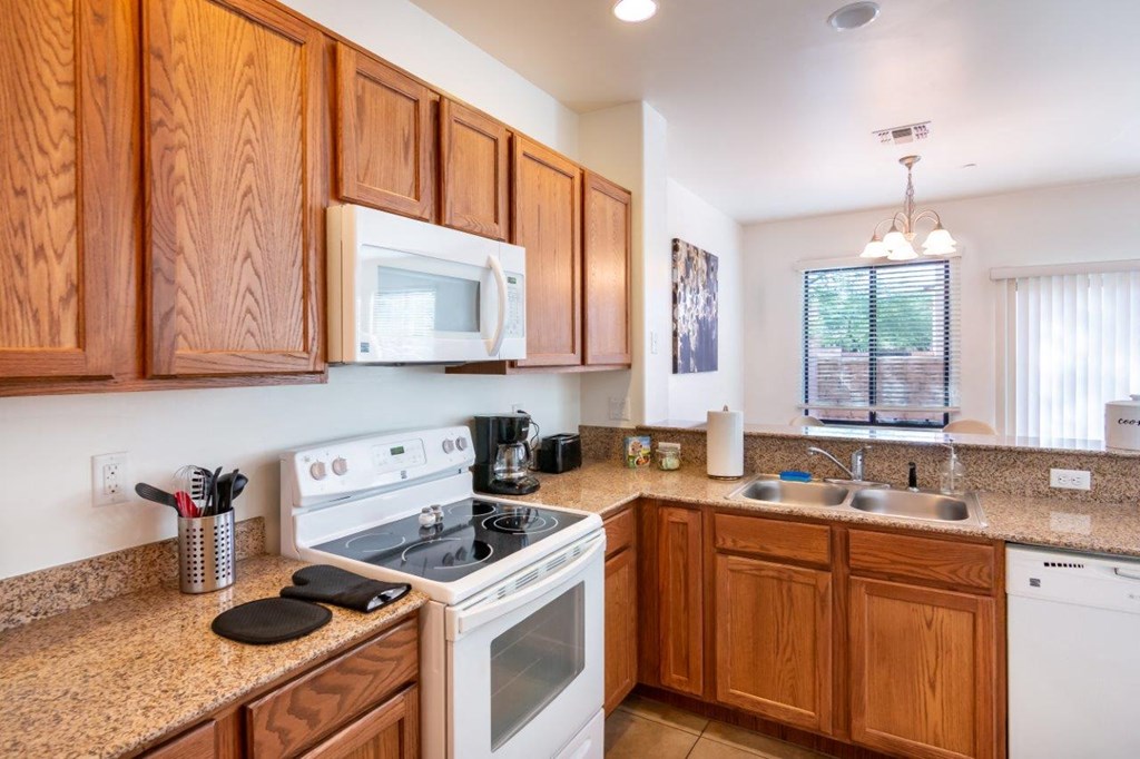 A kitchen with wooden cabinets and a white stove top oven.