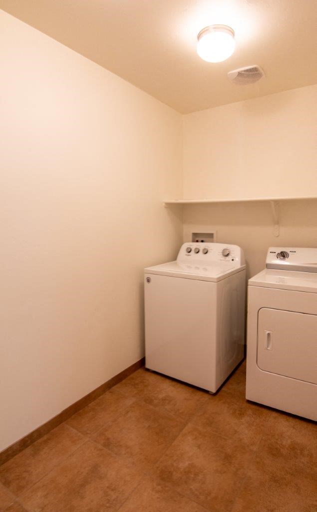 Two white front loading washing machines in a laundry room.