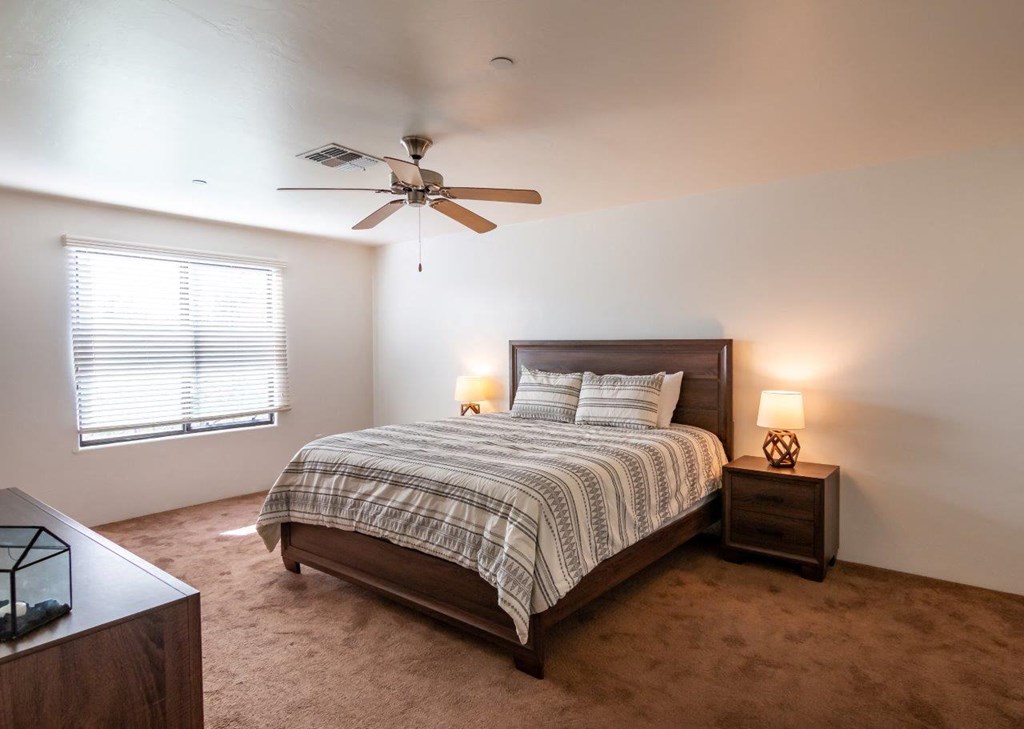 A bedroom with a bed, nightstand, and window.