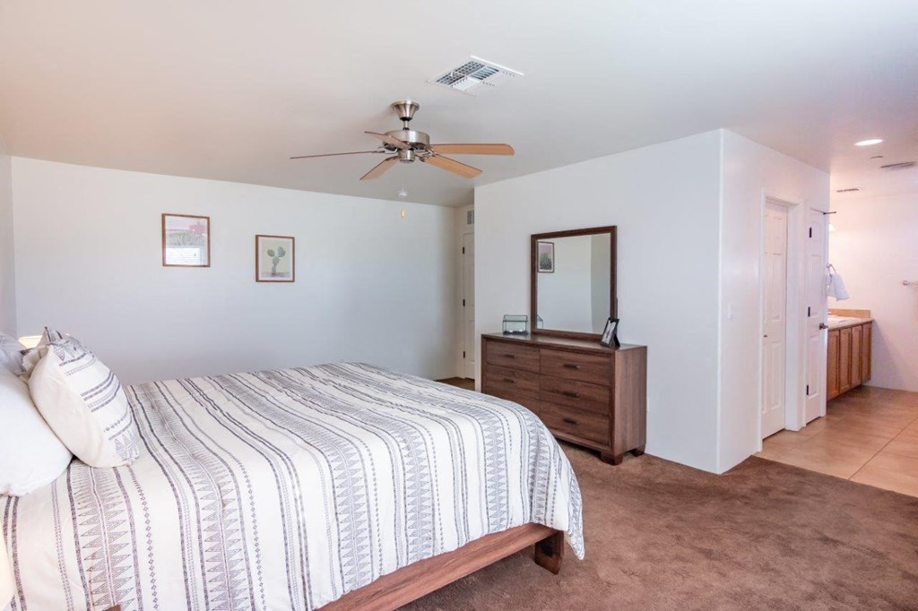 A bedroom with a bed, dresser, and mirror.
