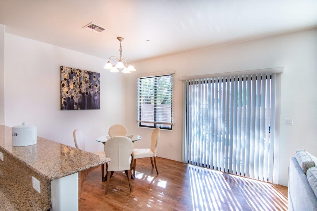 A kitchen with a granite counter top and a dining table with chairs.