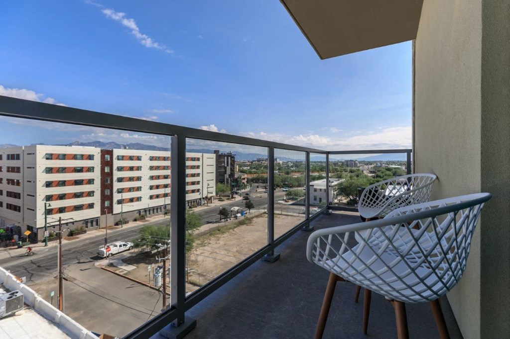 A balcony with a chair and a view of a street and buildings.
