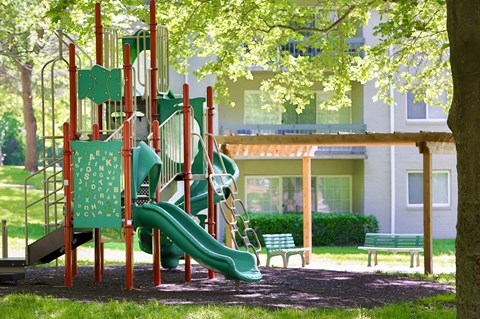 A playground with a green slide and a red structure.