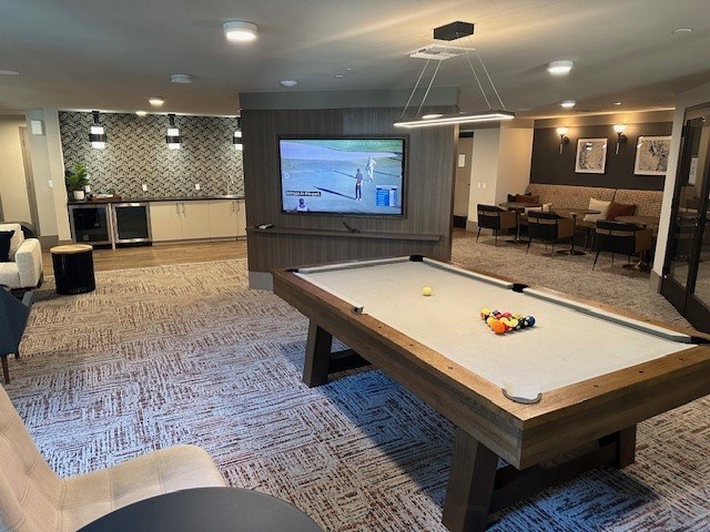 A room with a pool table and a television playing a movie.