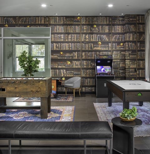 a living room with a wall of bookshelves and a pool table
