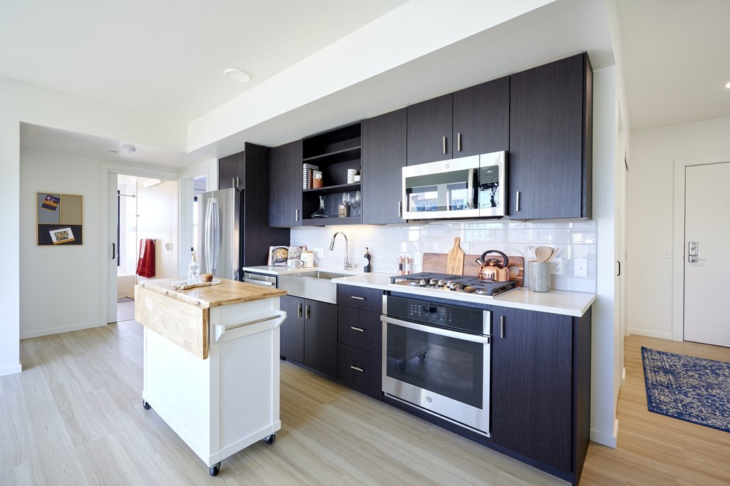 a kitchen with black cabinets and a white island in the middle