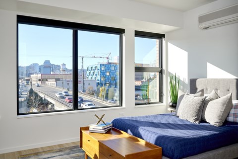 Bedroom with large windows and white walls at Grand Belmont Apartments in Central Eastside Portland, Oregon.