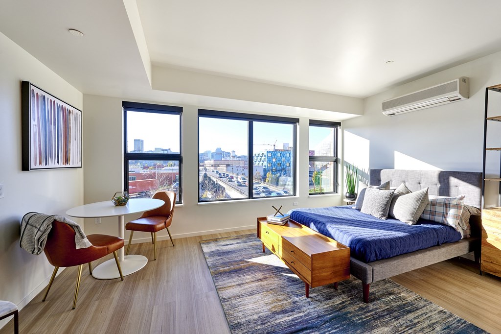 a bedroom with a bed and a table in a room with windows