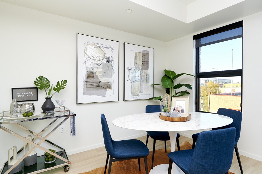 a dining area with a round table and blue chairs and a window