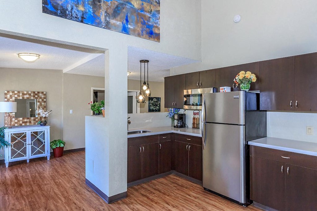 A kitchen with a refrigerator, sink, and wooden floors.