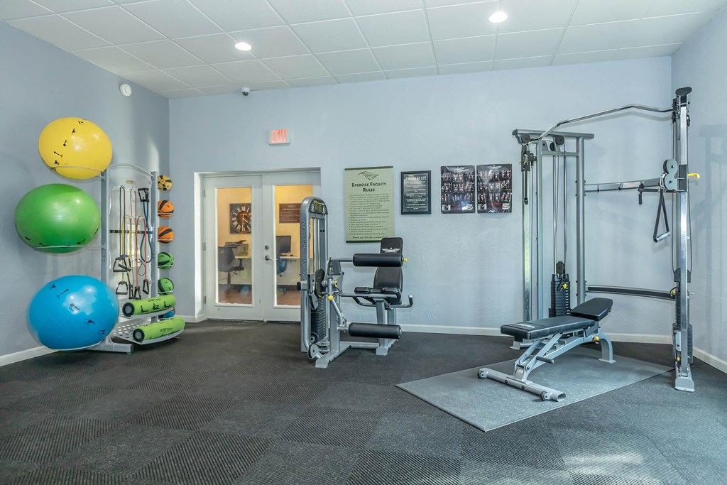 A gym with a variety of equipment including a leg press machine, a bench press, and a squat rack.