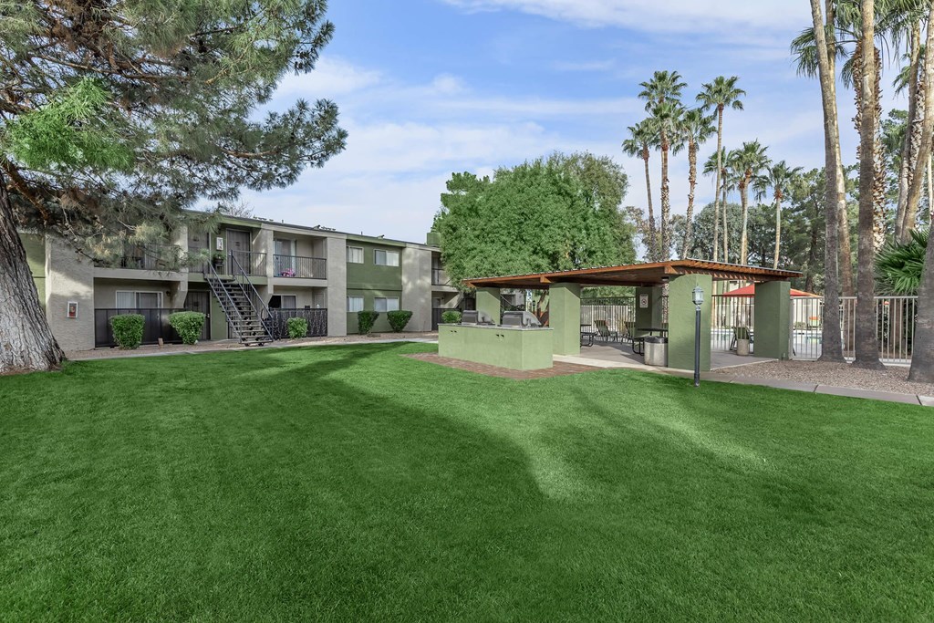 A grassy area in front of a building with palm trees in the background.